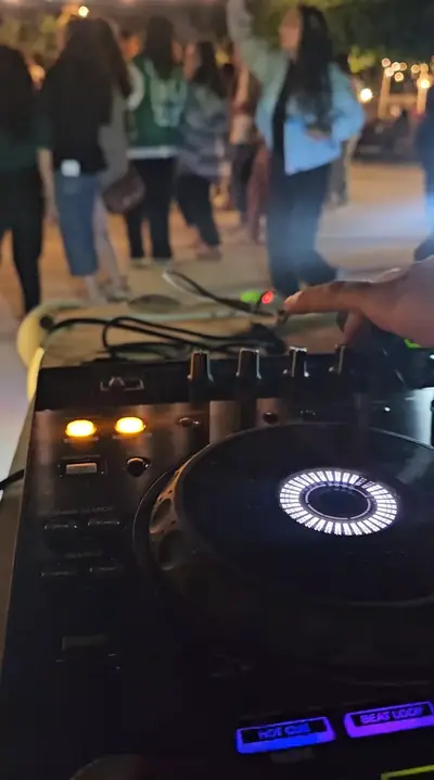 A DJ controller glowing at night in front of dancing guests