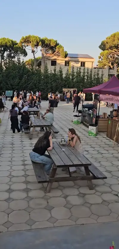 Guests at picnic tables in a paved square beside market stalls