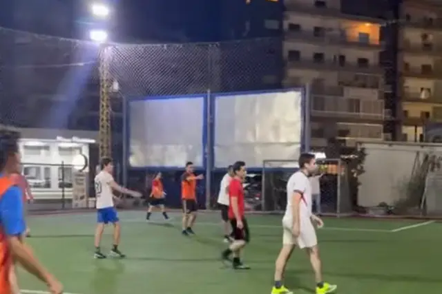An NCAS match under the floodlights, players spread across the pitch
