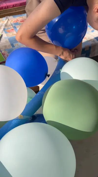 Hands tying blue and green balloons