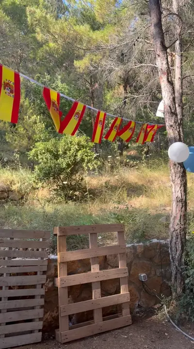 Spanish flag bunting strung between pine trees above wooden pallets