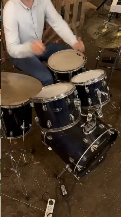 A drummer playing his kit among the trees
