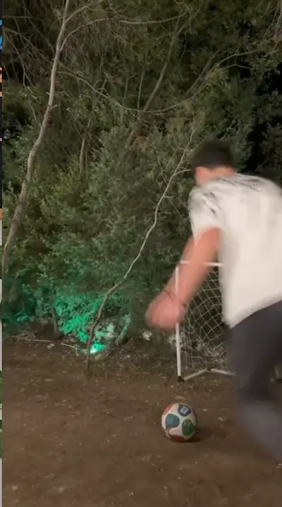A guest kicking a ball toward a small goal at night