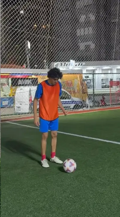 An NCAS player in an orange bib with the ball at his feet