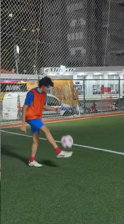 A player in an orange bib juggling the ball