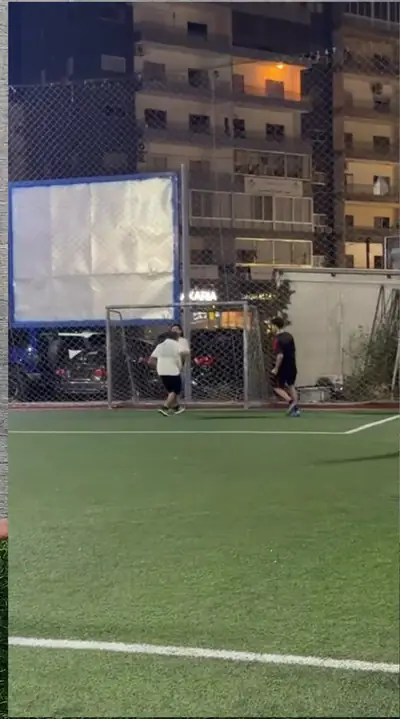 Players on a pitch surrounded by apartment buildings