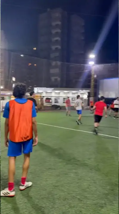 A player in an orange bib watching the game