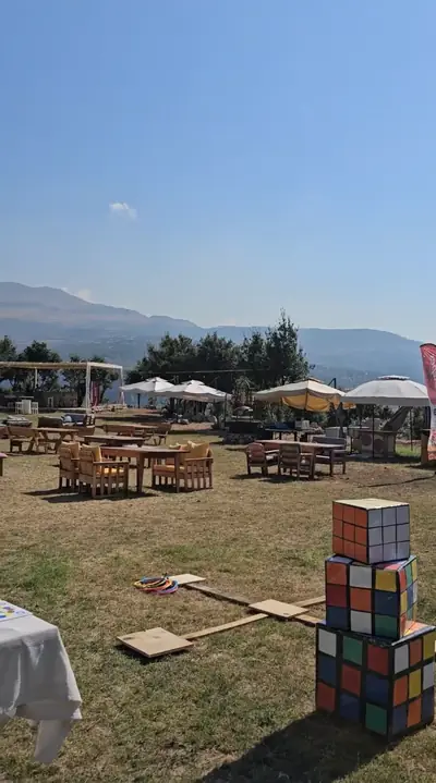 Giant Rubik’s cubes on a lawn with tables and mountains behind