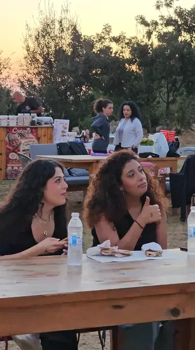 Two friends at a long wooden table at sunset