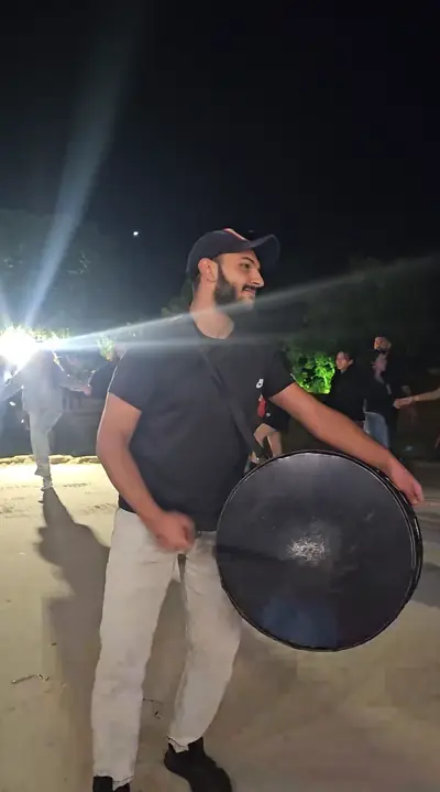 A musician playing a handpan at night