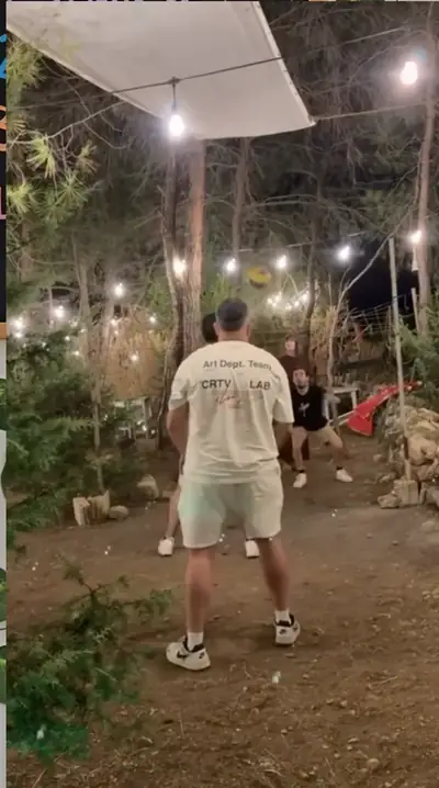 Guests playing volleyball under string lights in the forest